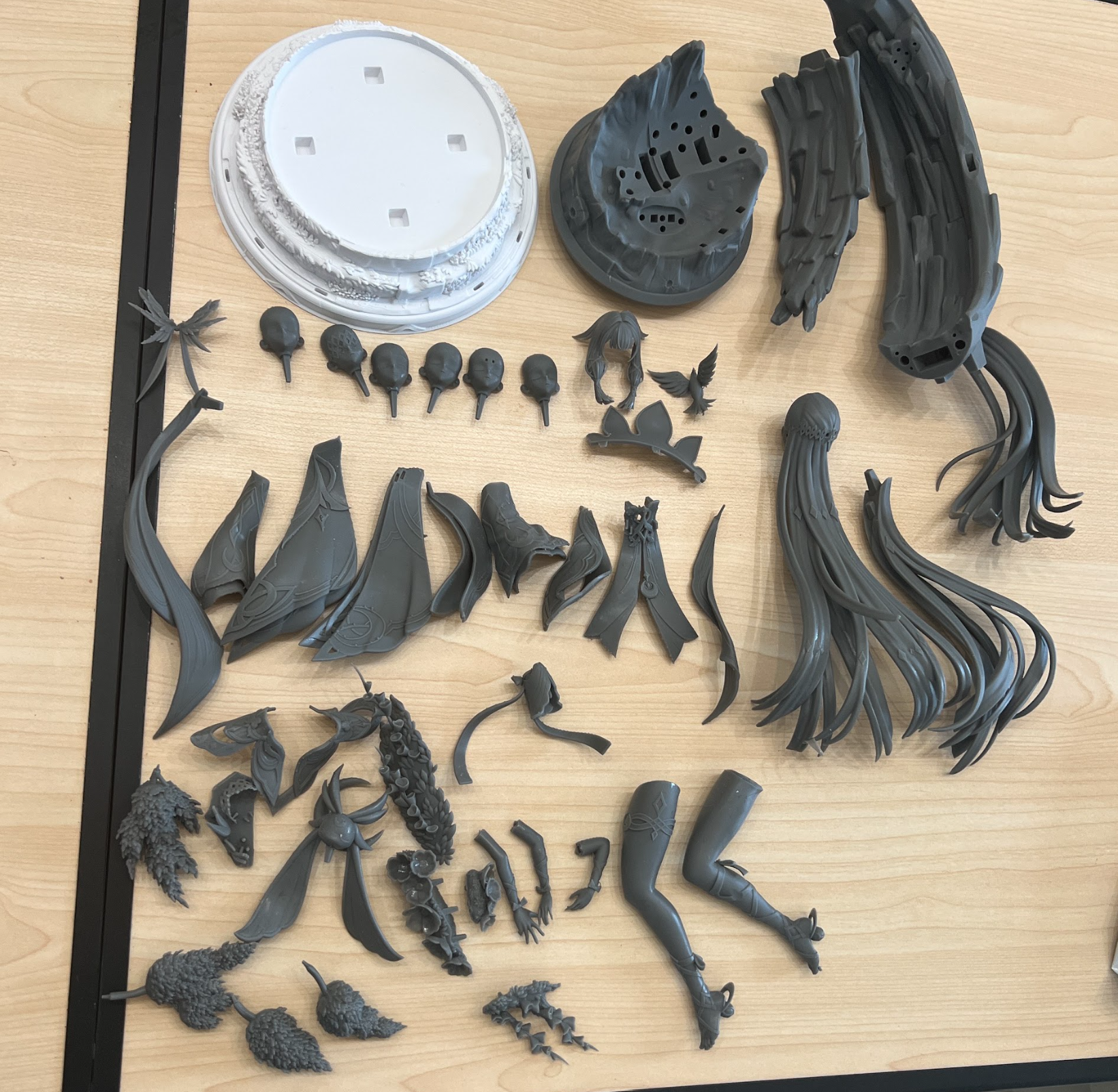 Resin figure components, faces, hair and bases arranged for assembly planning.