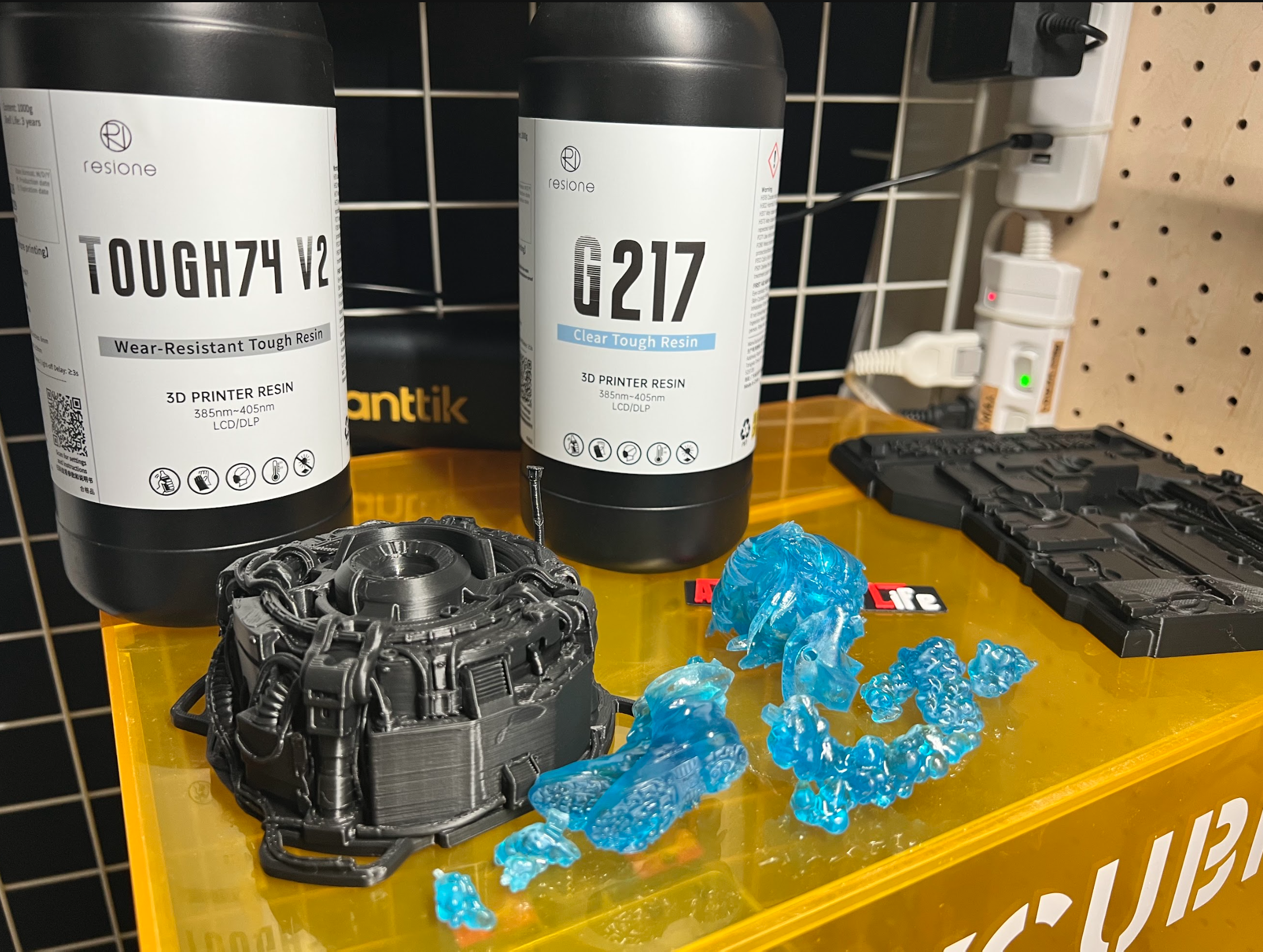 Opaque and transparent blue printed resin components beside material bottles.