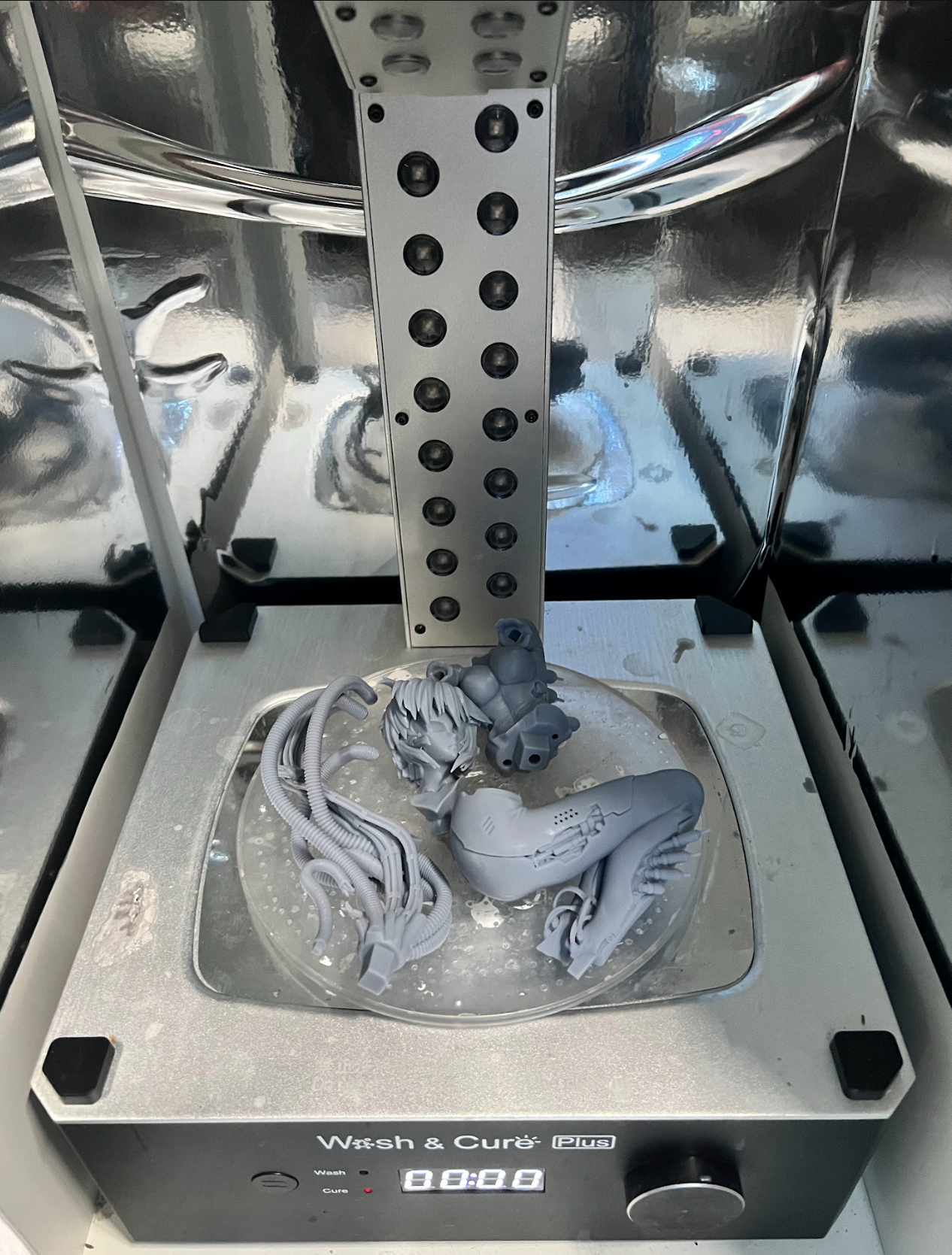 Separate gray resin model parts inside a curing station.