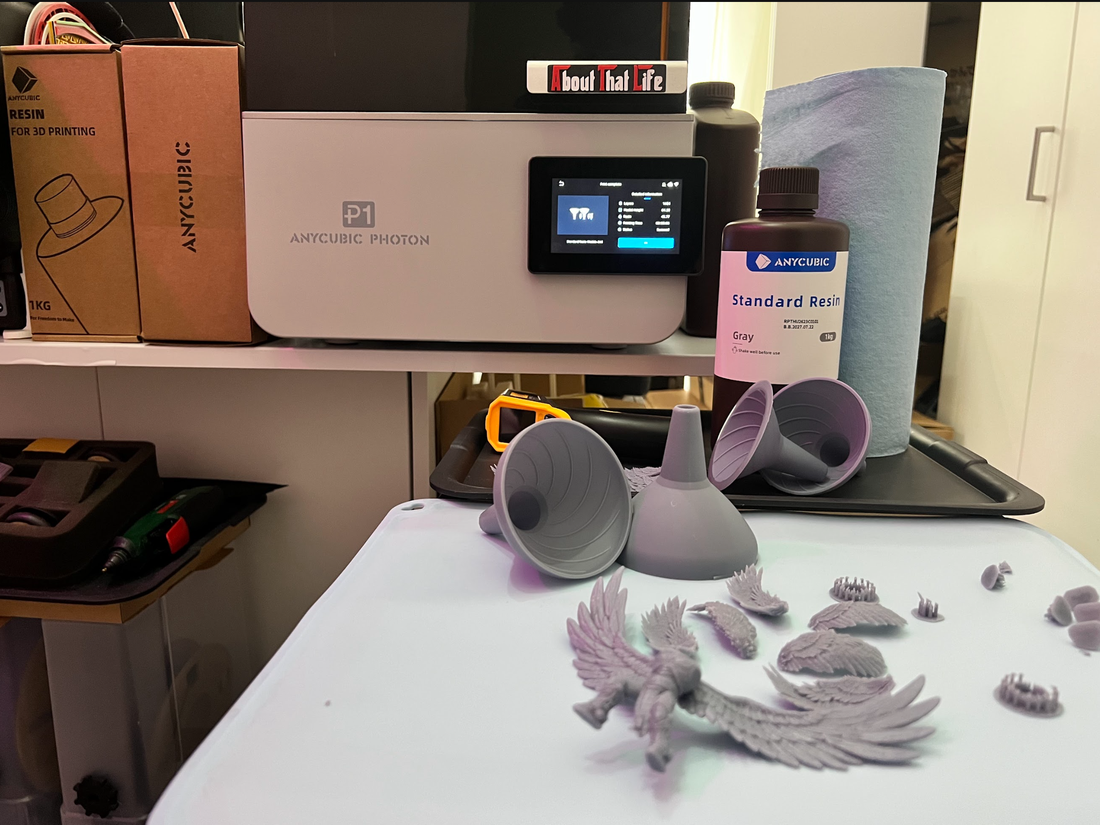 Resin printer, material bottle and freshly printed model components on a worktable.