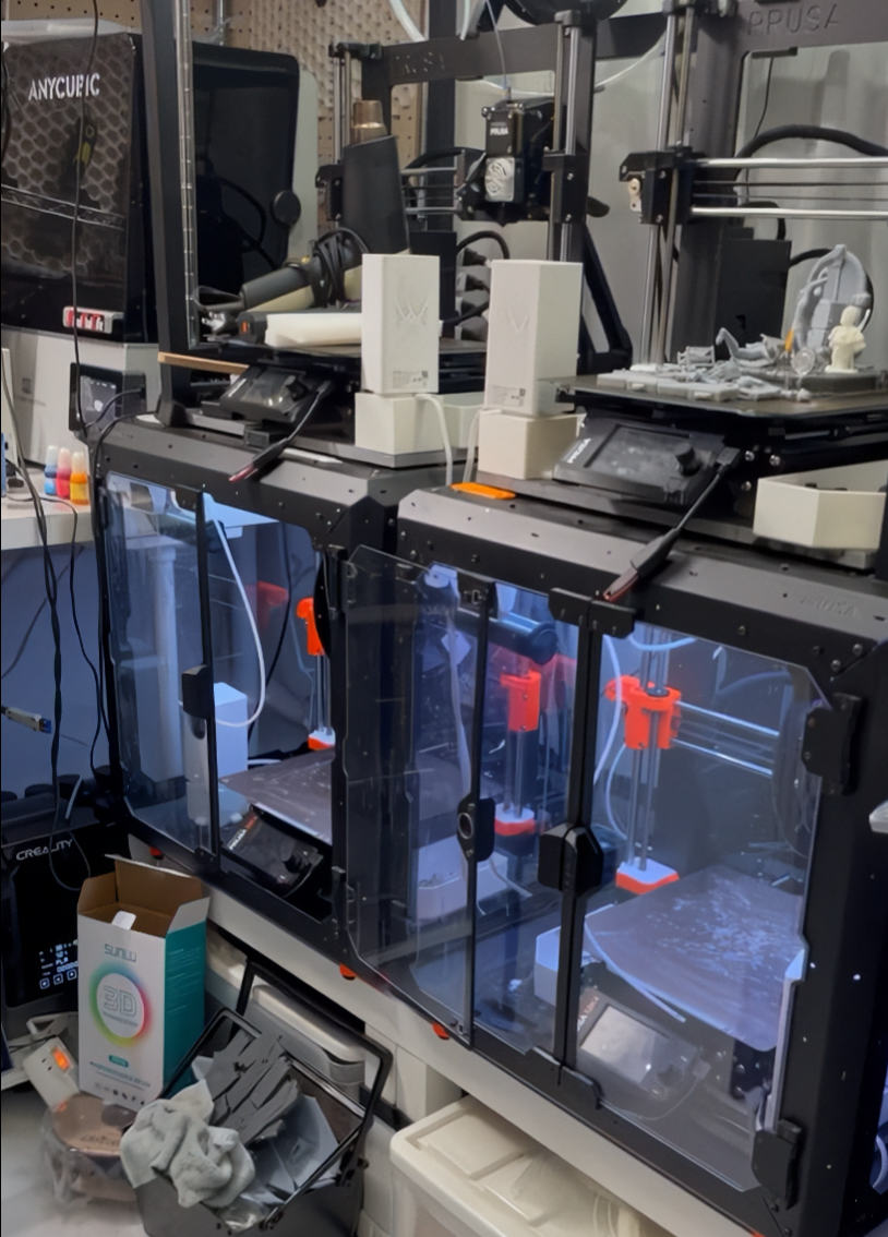 Enclosed and open-frame 3D printers arranged in Dan’s workshop.